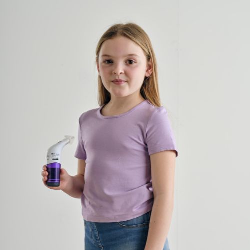 Child holding a handheld breathing training device against a plain background.